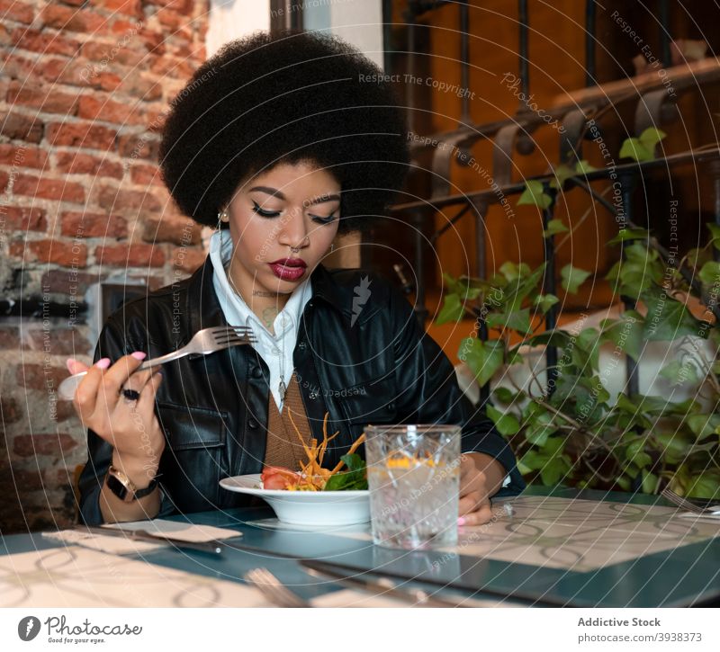 Young black woman eating salad in restaurant dinner portion cafe vegetable delicious food ethnic african american female drink dish meal lifestyle tasty yummy