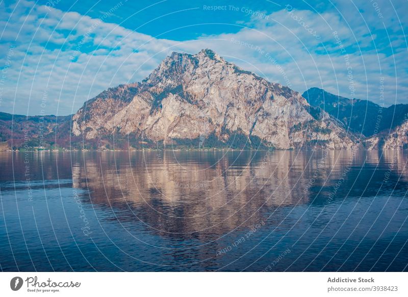 Rippling lake surrounded by rocky mountains against cloudy blue sky shore landscape nature range highland lakeside reflection scenic picturesque massive water