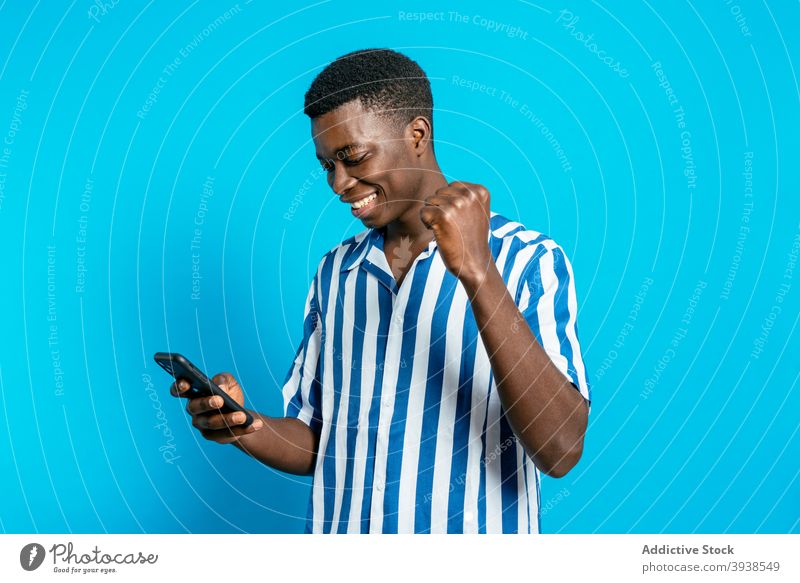 Black man celebrating victory with clenched fist good news cheerful celebrate winner clench fist luck delight smartphone male black ethnic african american
