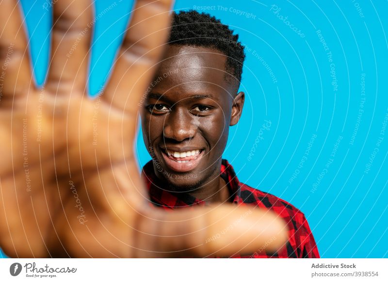 Content black man reaching hand to camera in studio cheerful checkered shirt style vivid color positive male ethnic african american plaid shirt vibrant young