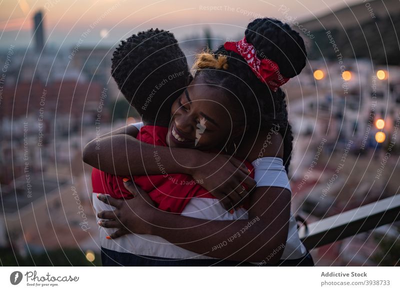 Happy young African American couple hugging on rooftop at sundown embrace happy love relationship affection city fondness date together sunset view boyfriend