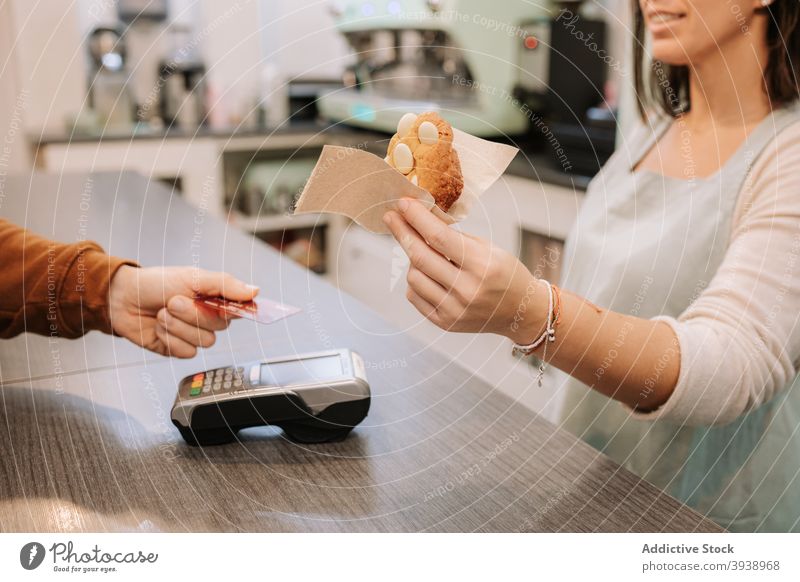 Seller giving sweet cookie to customer in confectionery cafe payment nfc credit card contactless serve terminal seller client food dessert purchase technology