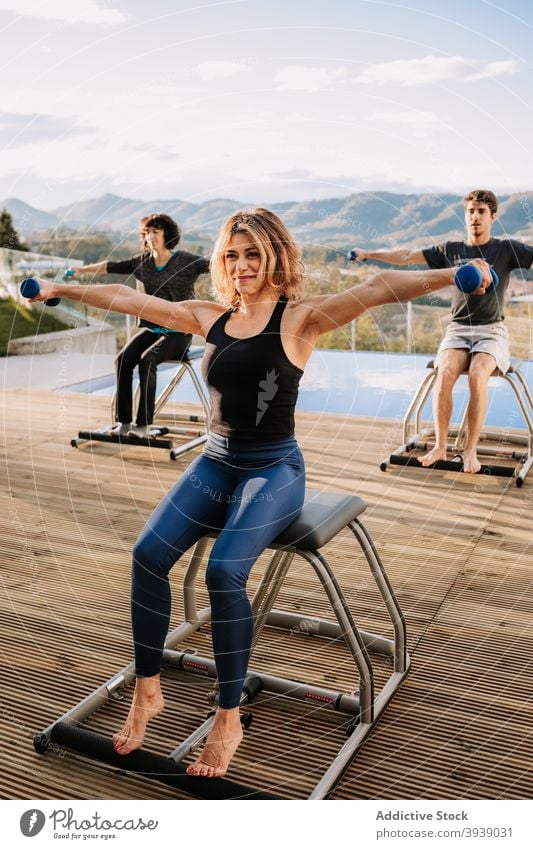 People during pilates workout on terrace exercise dumbbell chair cheerful practice training people together smile happy group sport wellbeing energy vitality