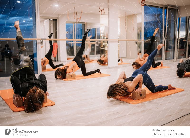 Group of people doing yoga in Downward Facing Dog pose in studio class practice group downward facing dog pose balance asana together