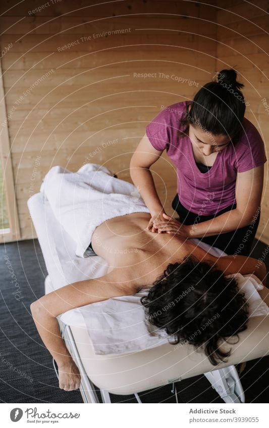 Crop masseuse doing massage for customer therapist client spa salon procedure lotion treat wellness wellbeing care pamper professional body health care apply