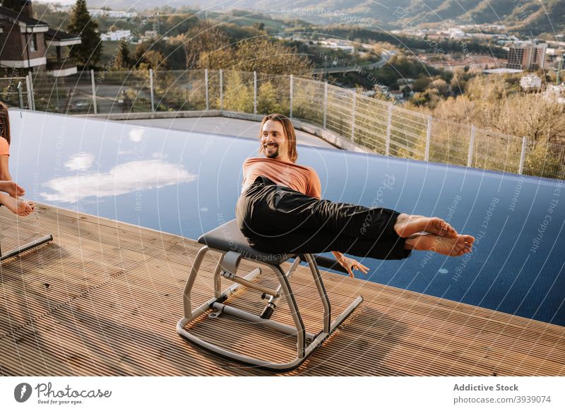Cheerful man doing abs exercise on pilates chair abdomen workout sportswear terrace cheerful male training physical wellbeing fitness wellness healthy energy