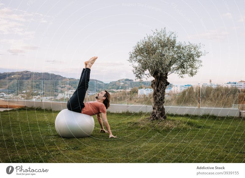 Man doing yoga in Wild Thing poses on fit balls pilates wild thing pose balance asana together flexible camatkarasana stretch lawn sportswear exercise wellness
