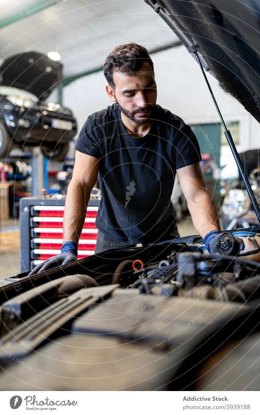 Mechanic checking car engine in workshop mechanic man oil examine inspect technician service male cap professional automobile job fix diagnostic transport