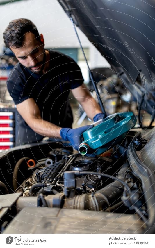 Male technician changing engine oil in car service man change motor pour maintenance male mechanic serious garage vehicle occupation job manual tool workshop