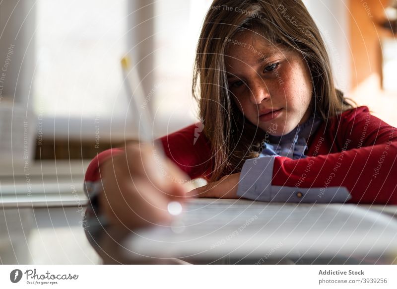 Focused girl doing homework task at table write paper concentrate assignment smart serious education knowledge exam preparation focus pupil child kid schoolgirl