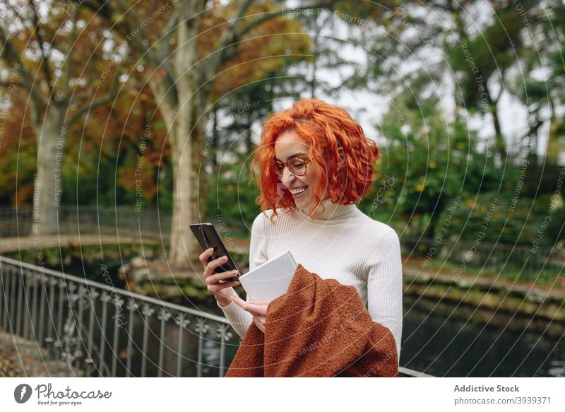 Peaceful redhead woman browsing smartphone in park appearance chat social media internet female red hair surfing online using mobile device tranquil relax