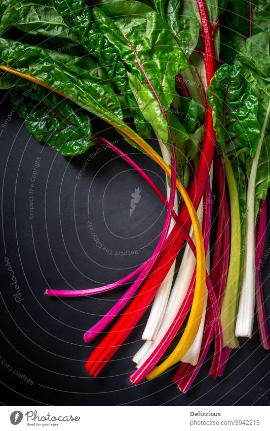 A bunch of beautiful rainbow chard on a black background, top down view closeup colorful cooking dark flat lay fresh freshness green harvest health healthy