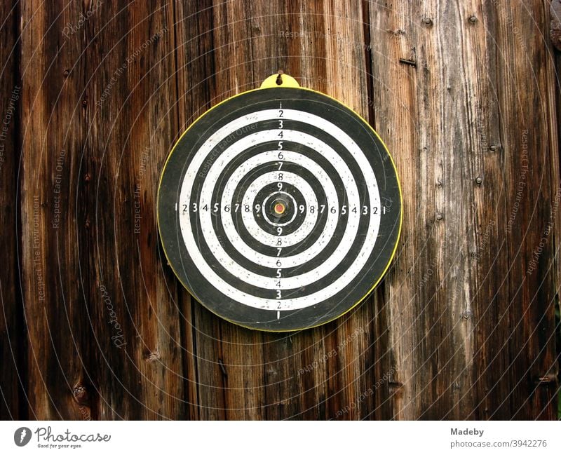 Round target for darts on the brown wood of an old barn on a farm in upper bavaria Target sheath Circle Sports free time entertainment Strike unerring figures
