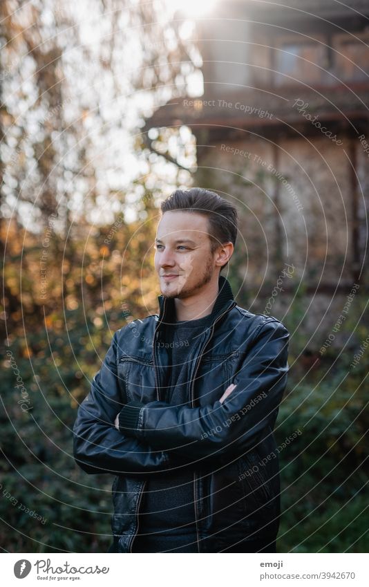 young man in leather jacket outside Outdoors Green masculine more adult Cool (slang) Upper body arms folded Profile Young man Man Friendliness Smiling Positive