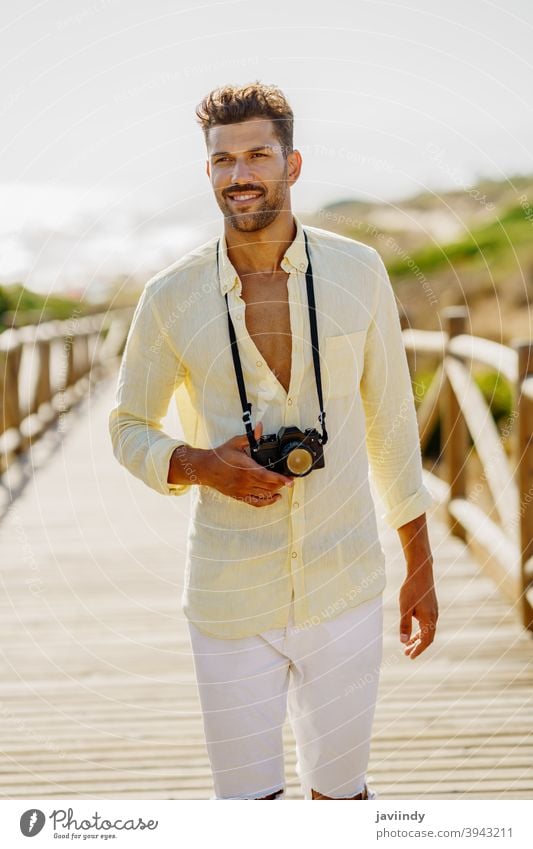 Smiling man photographing in a coastal area. photographer camera traveler tourist beach summer photography nature tourism vacation toothy smile holiday smiling