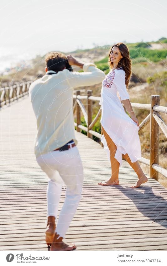 Man photographing his girlfriend on a lovers' trip. couple vacation photographer woman traveler tourist resort people nature leisure summer tourism spanish guy