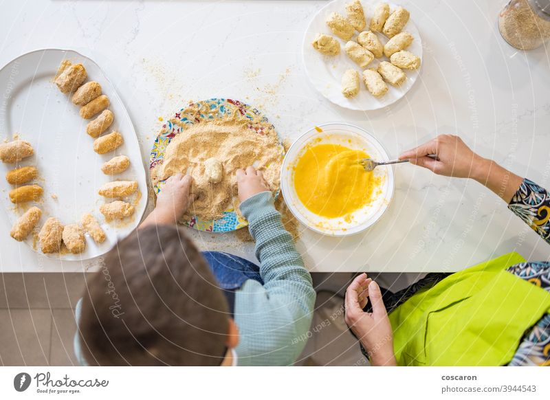 Mother and son making croquettes in the kitchen adult beautiful bowl bread crumbs caucasian child childhood cook cooking cute domestic dough egg eggs enjoyment