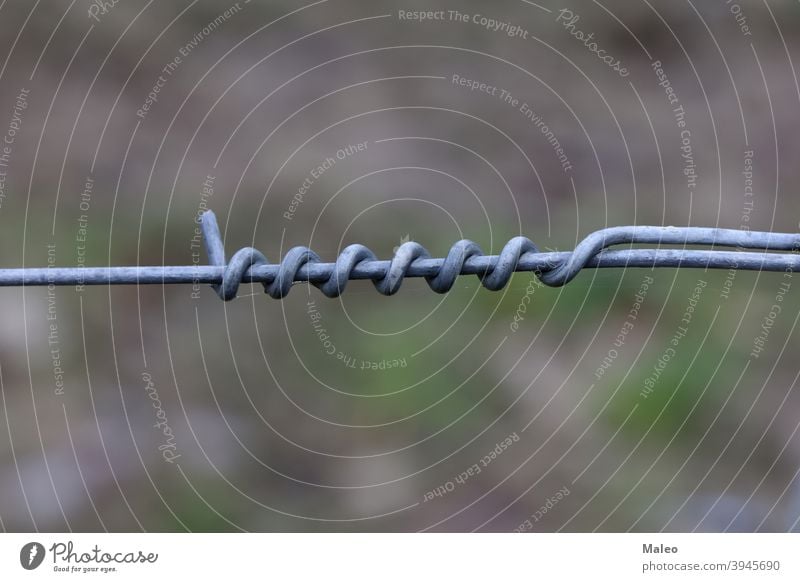 Twisting of metal wire on an electric fence steel prison protection sharp barbed barbwire barrier boundary detail energy spiral twist security crime criminal