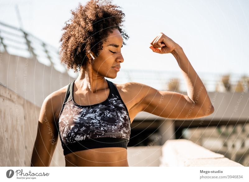 Afro athlete woman flexing and showing muscles. fitness sport exercise resting break outdoor relax enjoying relaxation leisure ear pods sporty relaxing