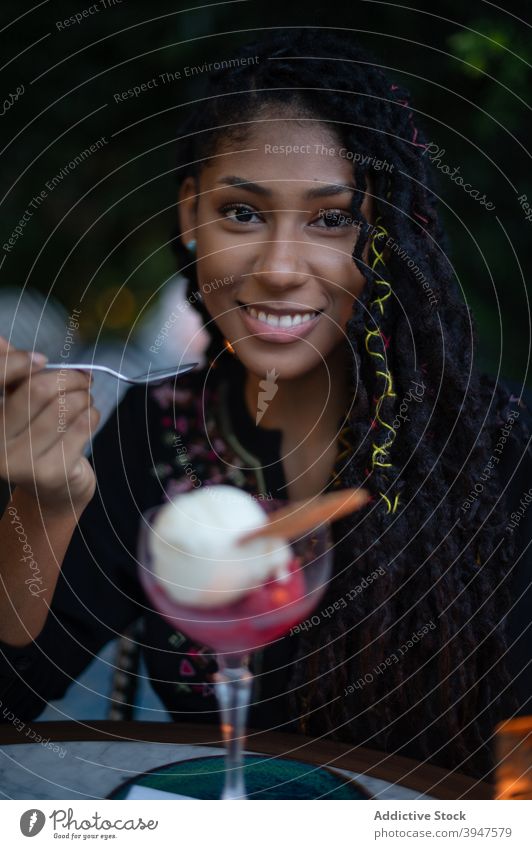 Afro latina woman eating ice cream in restaurant happy enjoying cafe smiling 20s young female Colombia afro black attractive dreads lifestyle mixed race tasty