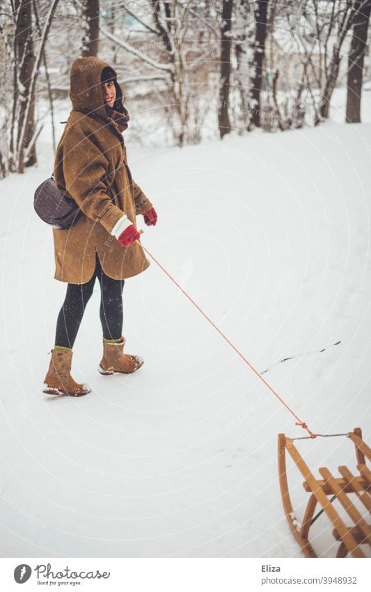 A woman pulls a sled through the snow in winter Snow Sleigh Sledding Joy Winter Woman Laughter Brunette Snowscape snowy Coat White Nature Cold Human being