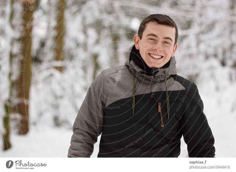 Winter - happy young man having fun in snow and laughing, smiling into the camera portrait winter teenager happiness joy boy guy cold skiing outdoor snowy male