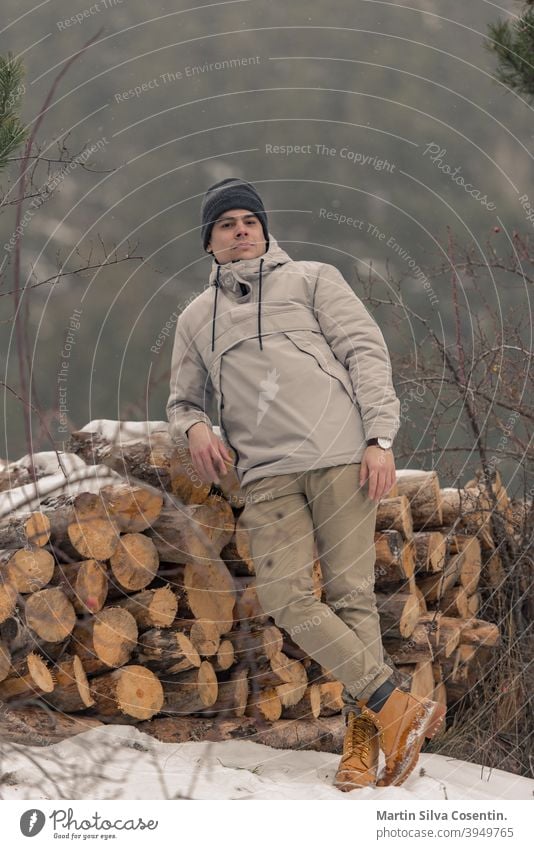 Young man in the field on firewood in winter with snow background beautiful boots closeup clothes cold concept design fashion foot footwear forest frost hiking
