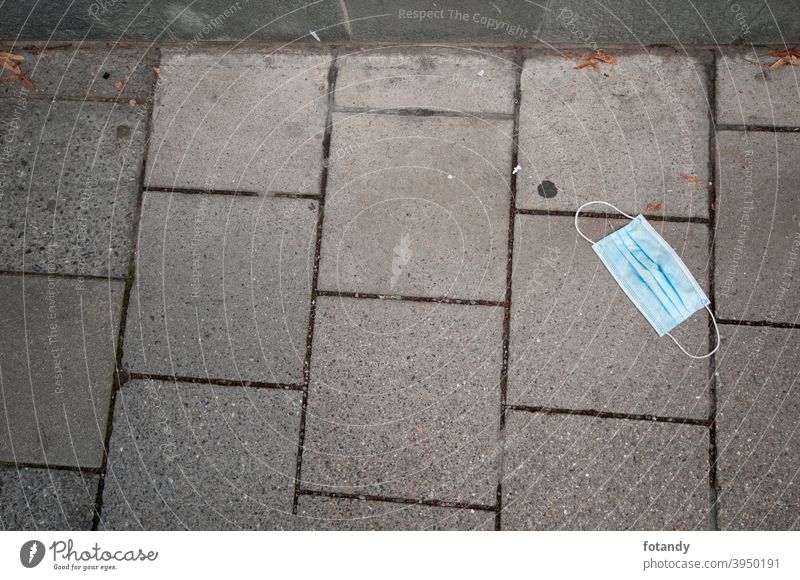 Einwegmaske auf dem Bürgersteig Objekt draußen Mund-und Nasen-Maske Schutzmaske medizinisch blau hellblau niemand Gehweg Beton Gehwegplatten Fugen Müll