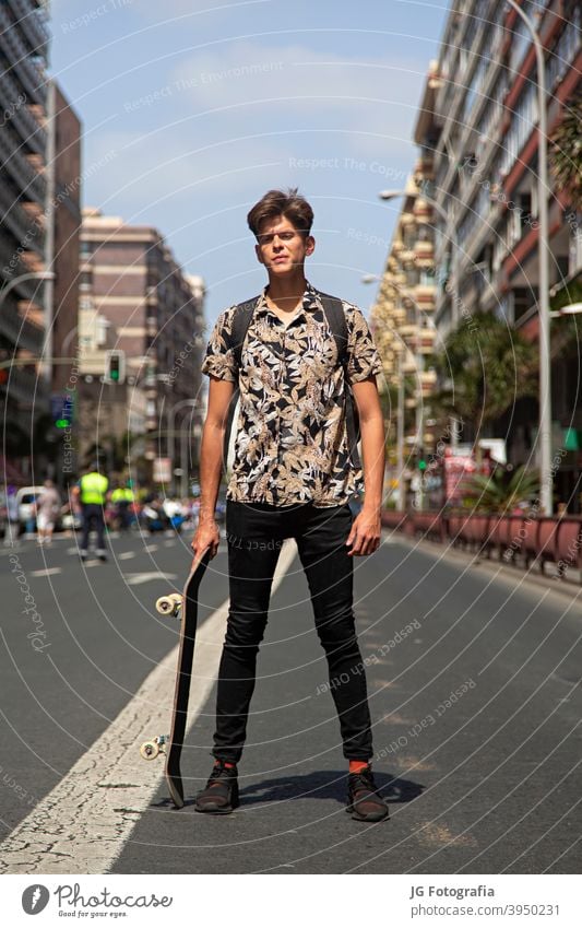 Portrait of authentic young man with skateboard in the middle of the street. portrait guy skateboarder urban model fashion retro attitude look gaze face poster
