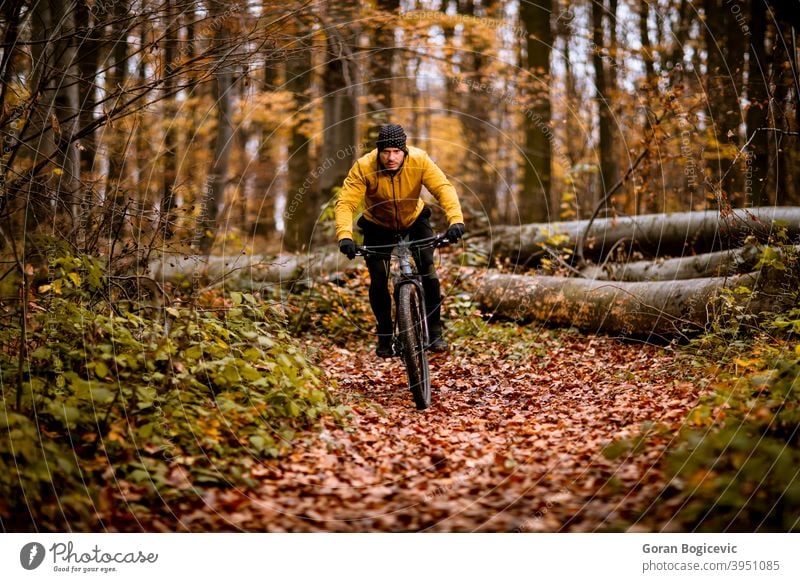 Young man biking through autumn forest bicycle bike nature ride cyclist biker lifestyle outdoor sport exercise trail mountain action extreme recreation tree