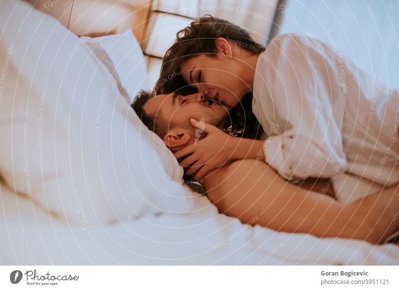 Beautiful young loving couple lying in bed adult attractive bedroom caucasian embracing handsome happiness happy home horizontal lifestyle love male man morning