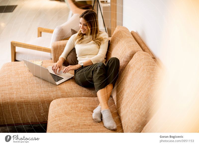 Young beautiful woman using a laptop at home sofa internet computer technology room beauty leisure pretty living lifestyle young couch female person happy