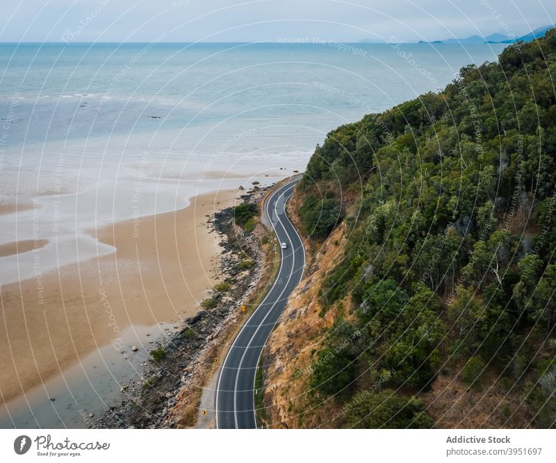 Highway in mountainous terrain near picturesque ocean with sandy coast road beach hill tree nature landscape seascape car journey route scenic great ocean road