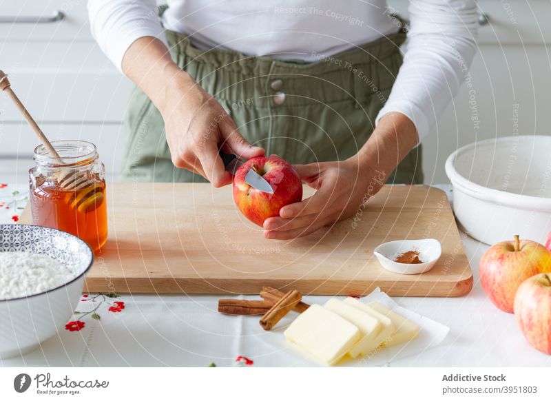 Crop person cutting apple for pastry prepare ingredient fresh board food fruit flour butter honey cinnamon crumble recipe table sweet knife kitchen slice peel