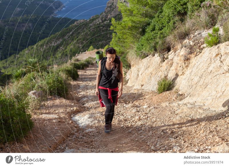 Active young female hiker walking along rocky path during trekking in mountains woman trail backpacker nature sea valley highland activity hobby activewear