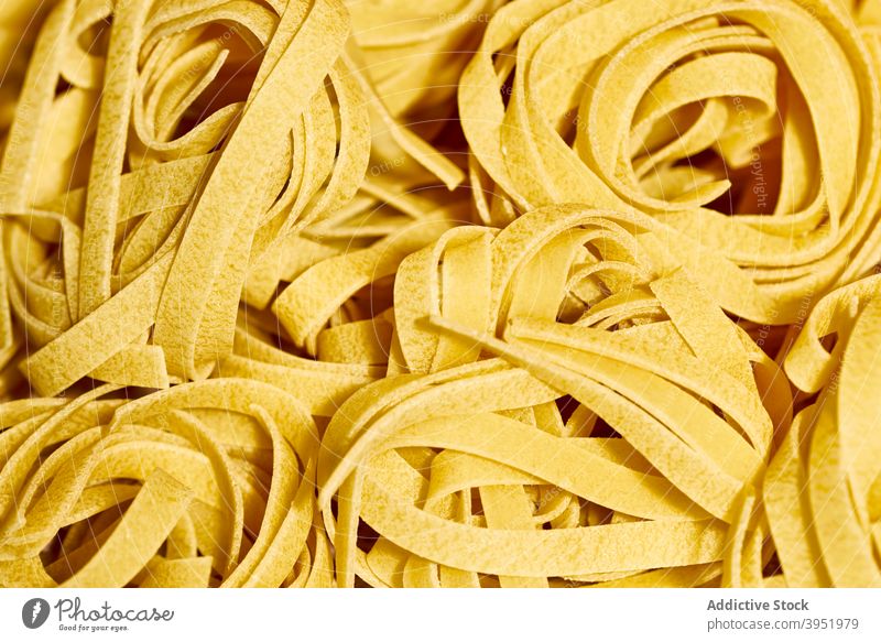 Uncooked Italian pasta fettuccine tagliatelle nest italian cuisine raw uncooked tradition delicious meal food composition ingredient yellow table culinary