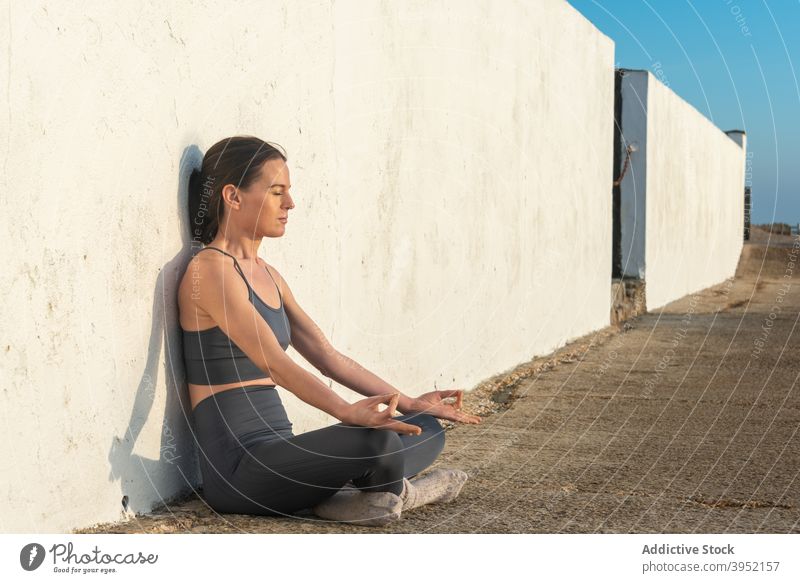 Slim woman meditating near wall yoga meditate lotus pose asana padmasana barefoot zen harmony female mudra gesture wellness peaceful balance position