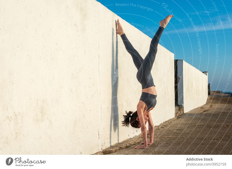 Slim woman doing yoga in handstand position near wall practice asana harmony balance flexible female zen lean wellness slim mindfulness calm stress relief sunny