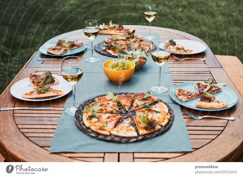 Dinner in a home garden. Pizza, salads, fruits and white wine on table in a backyard beverage celebration dinner dish drink eating feast food gathering having