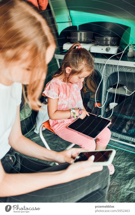 Sisters spending time in a tent on camping. Children using tablet playing games online during summer vacation children girl siblings sister family internet