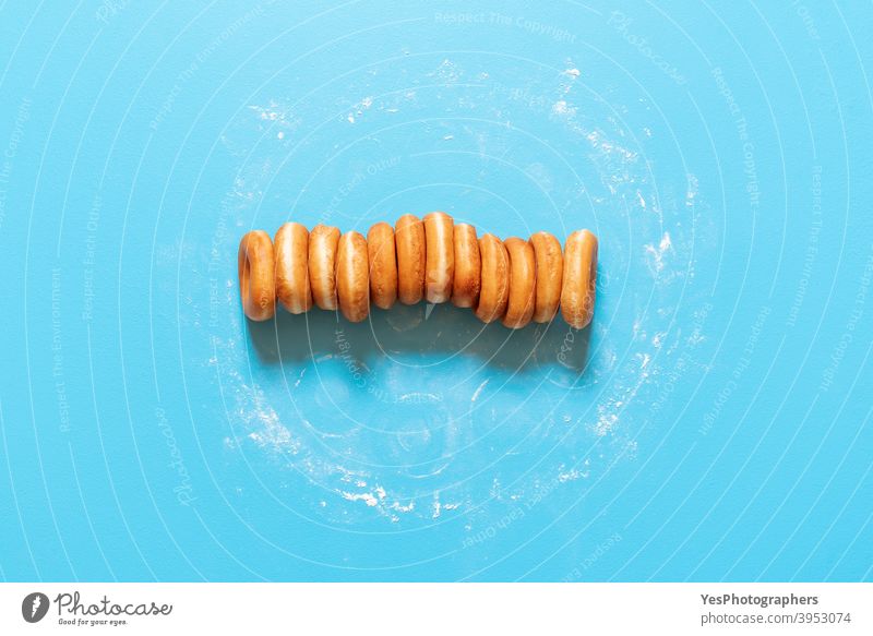 Donuts in a row on blue background. Homemade ring doughnuts, top view aligned american baked bakery breakfast cake calories comfort food confectionery cuisine