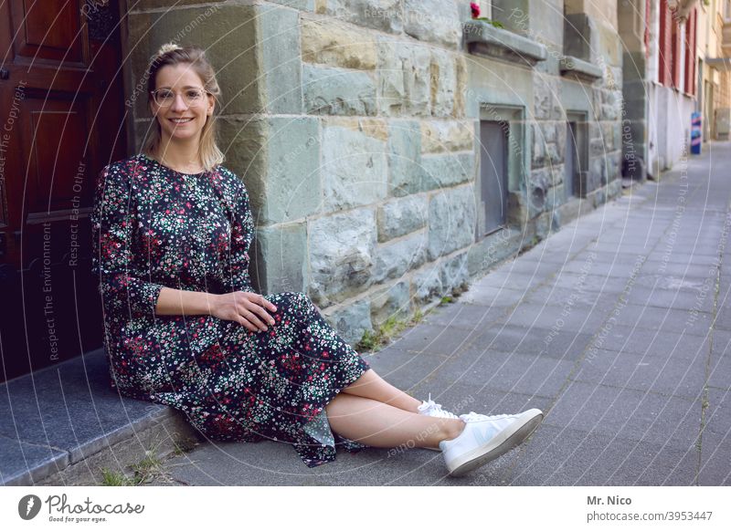 young woman sits in front of the house door and waits Sit Wait Facade Building Old town Front door Entrance House (Residential Structure) Summer dress Sidewalk