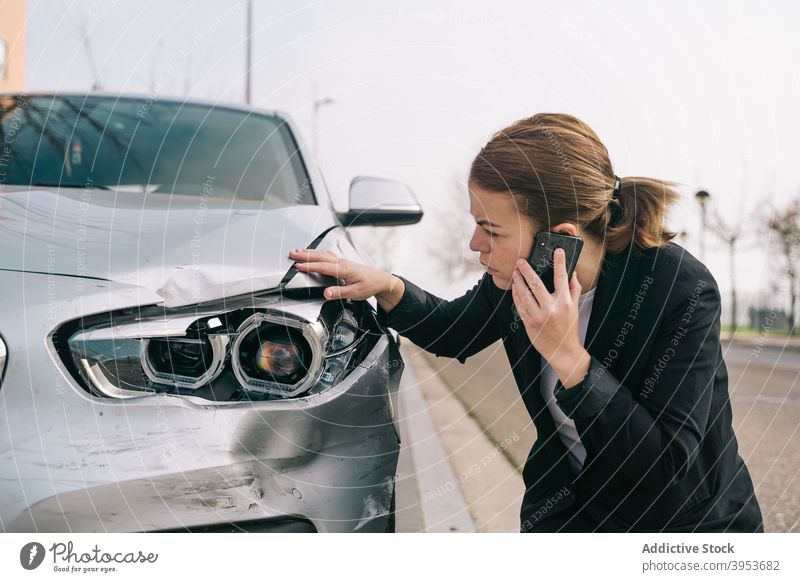 Serious young lady talking on phone and checking car damages after accident woman phone call crash broken upset smartphone insurance female driver casual