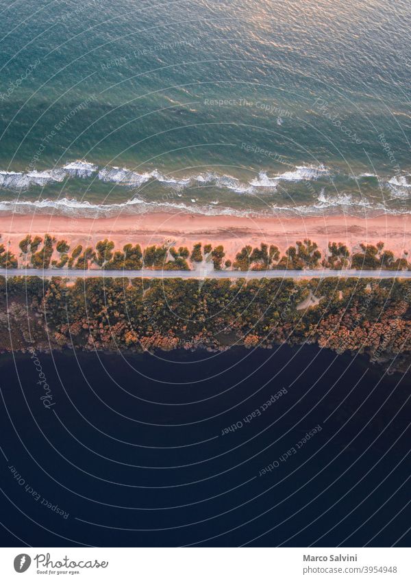 Drone view of a road running along the coastline between the sea and a lake drone drone view above Bird's-eye view dune beach trees nature waves ocean water
