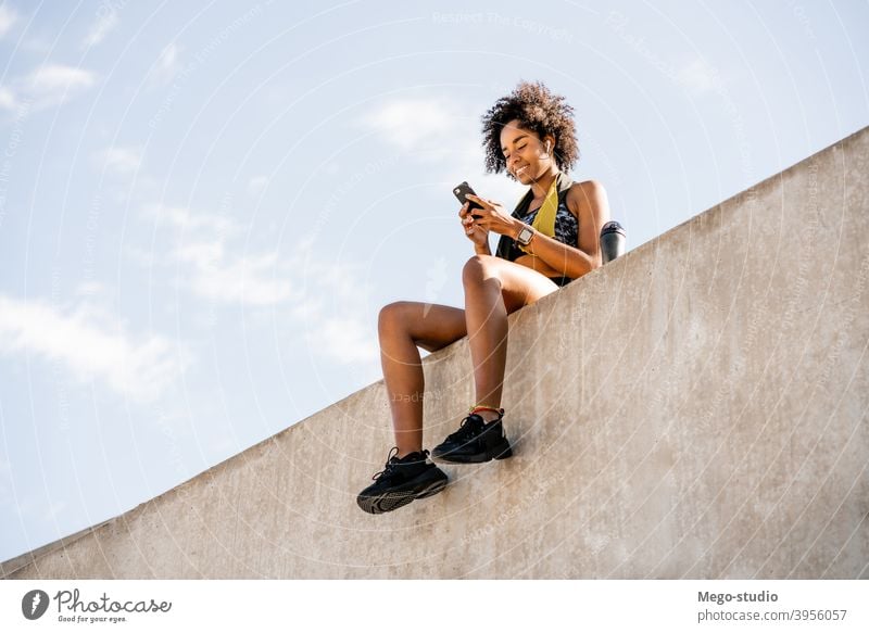 Athlete woman using her mobile phone outdoors. athlete fitness gym rest relax active portrait gadget activity urban black sporty sportswoman app city people