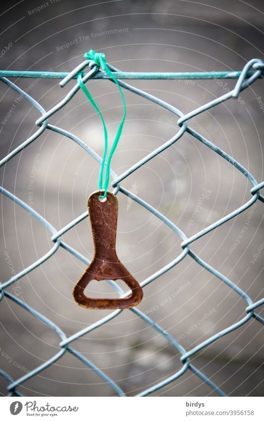 rusty bottle opener hangs on a wire mesh fence. Close up , weak depth of field Bottle opener Fence Wire netting fence Hang ribbon ready to hand Opener