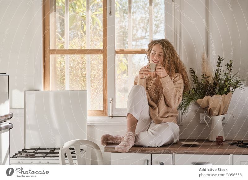 Woman drinking coffee in kitchen woman carefree enjoy morning home aromatic counter female relax sit cup fresh breakfast beverage rest cozy energy mug happy