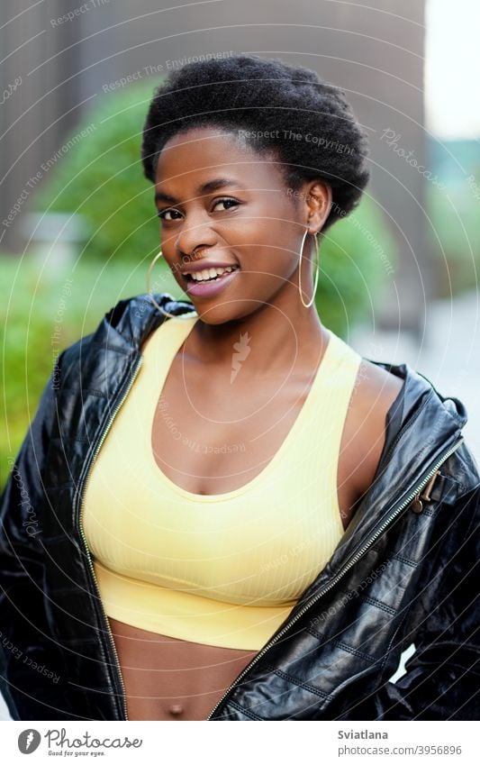 Young African American woman wearing a jacket smiles and looks at the camera girl black portrait african happy young american posing looking smiling laughing
