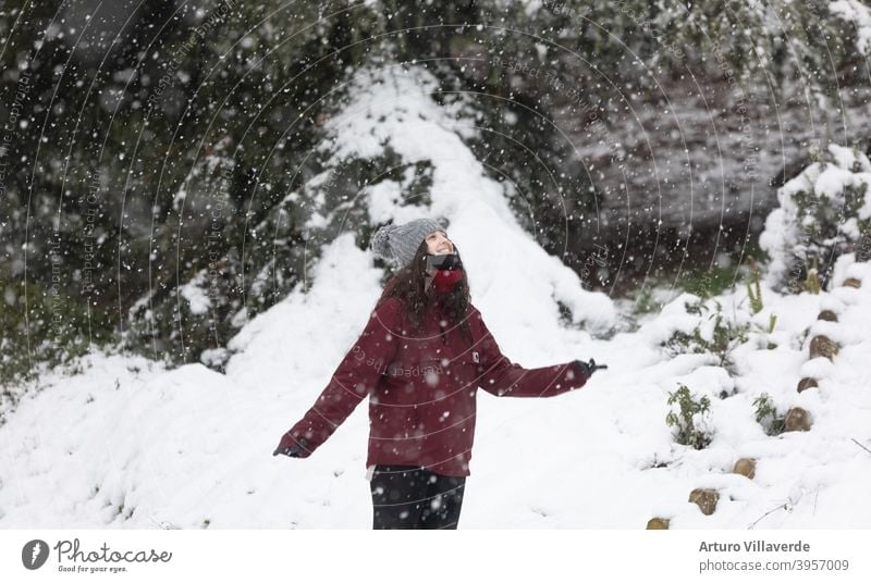 young woman in the snow, wears a gray cap and a red coat. He's smiling looking up at the sky pretty Close-up Markets Hooded (clothing) Fashion Happy blow frisky