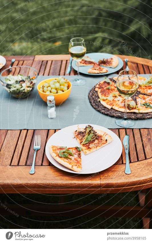 Dinner in a home garden. Pizza, salads, fruits and white wine on table in a backyard beverage celebration dinner dish drink eating feast food gathering having